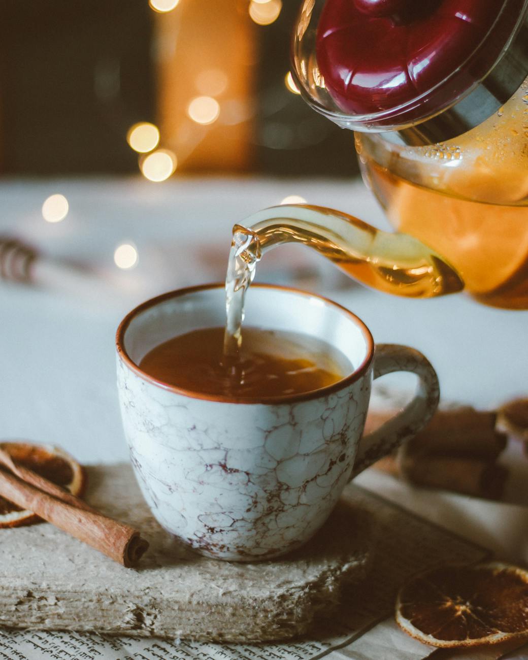 person pouring tea on white ceramic teacup Happy Tea: Uplifting Herbs for the Winter Blues
