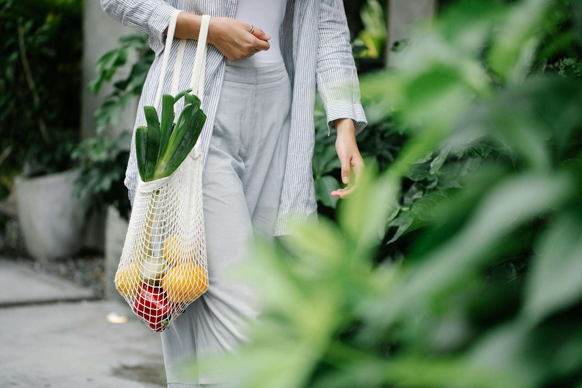 crop unrecognizable woman carrying bag with organic vegetables in garden