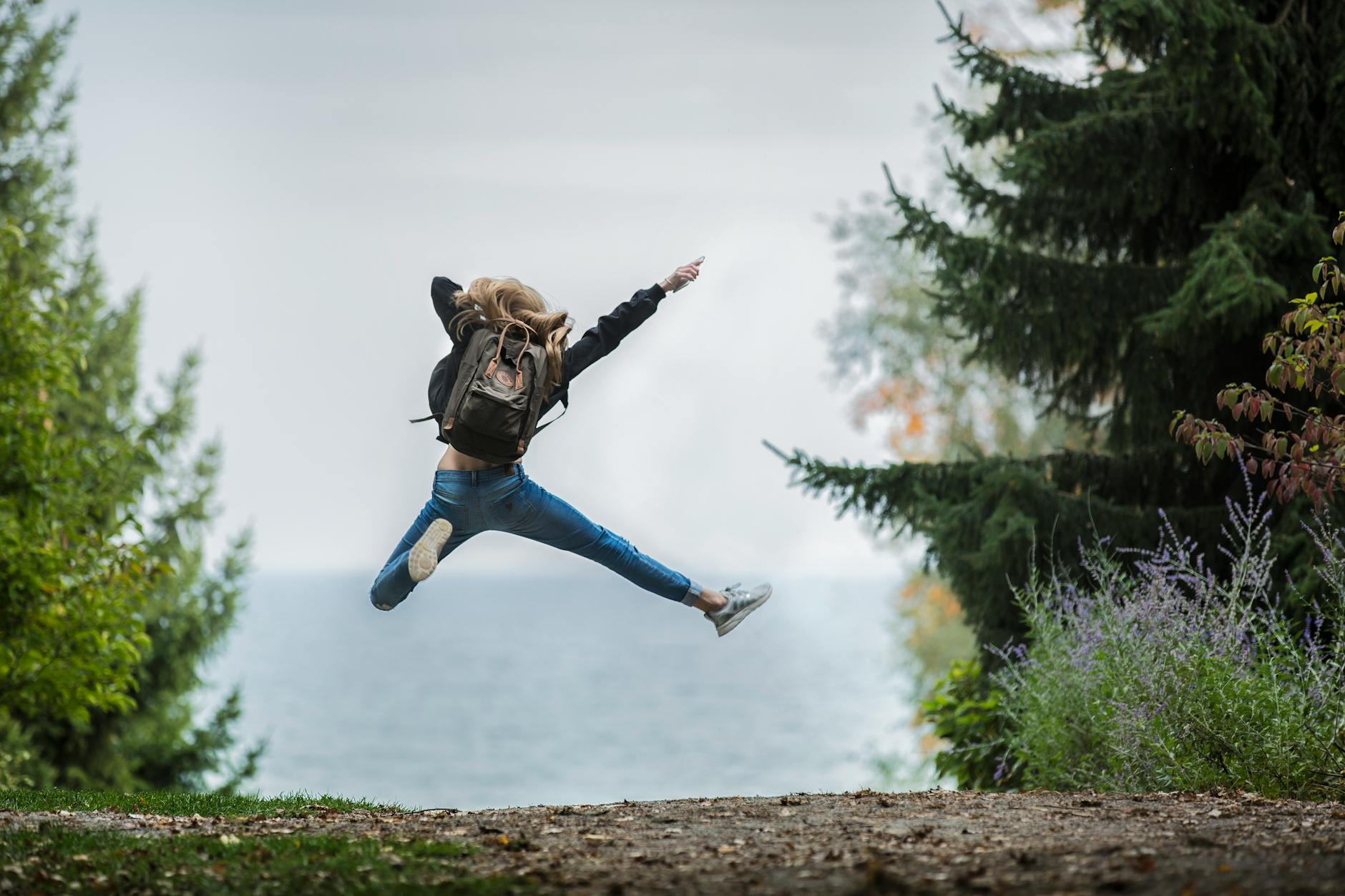 woman jumping wearing green backpack How to Boost Self Confidence
