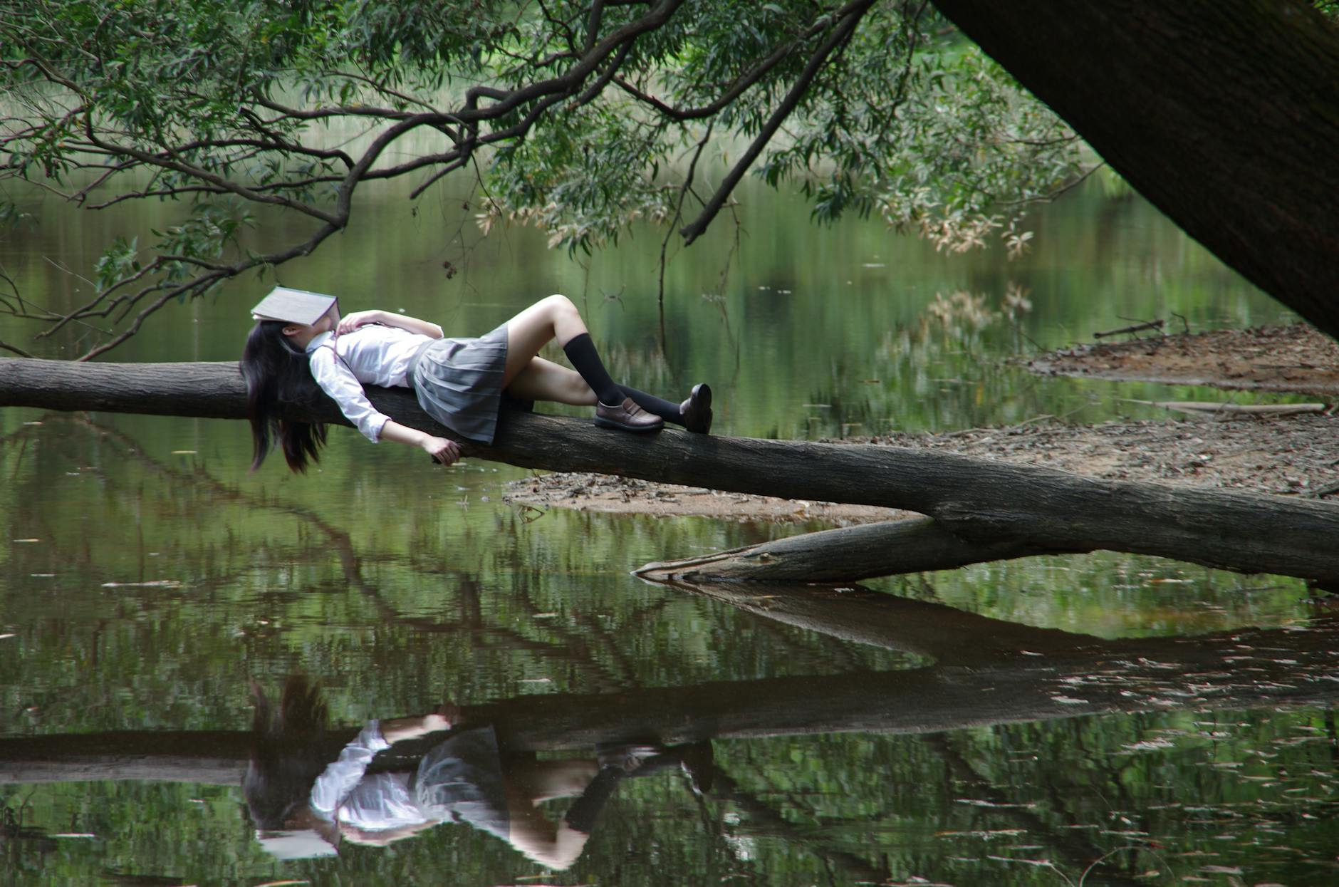 woman lying on tree near awter