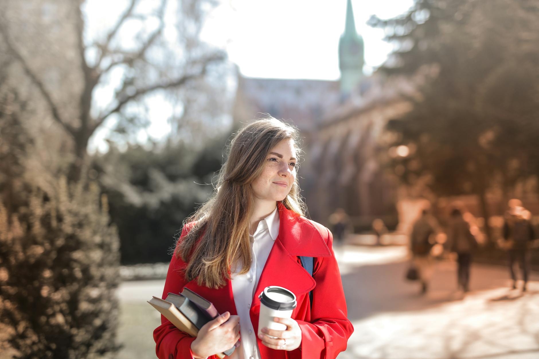 woman in red coat holding notebooks and coffee cup Getting Your Child Through College: Important Financial Considerations
