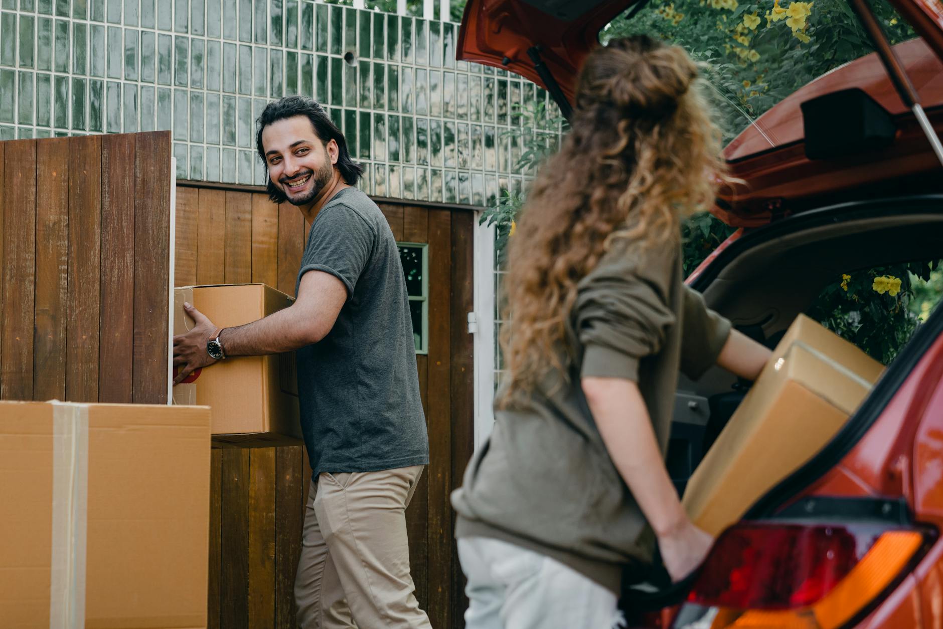 happy couple unloading automobile while moving apartment in summer day moving