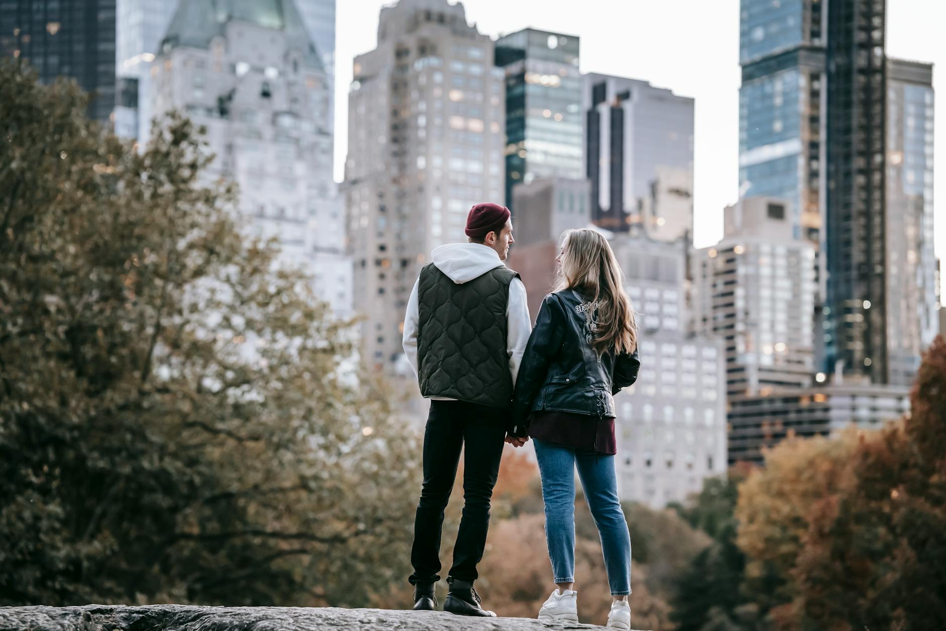 couple holding hands against urban buildings in park Romantic Getaway Ideas to Rekindle Your Love