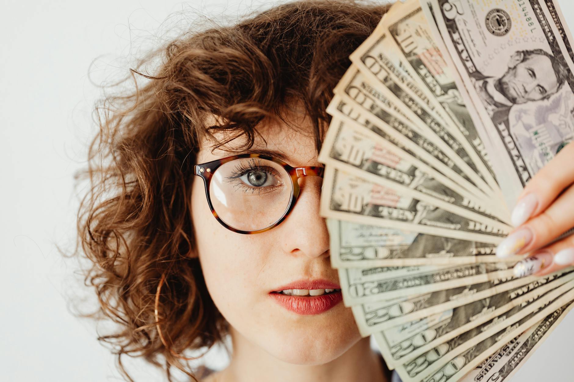 The Biggest Life Milestones You Will Experience in Adulthood 10 woman in eyeglasses covering her face with paper money The Biggest Life Milestones You Will Experience in Adulthood