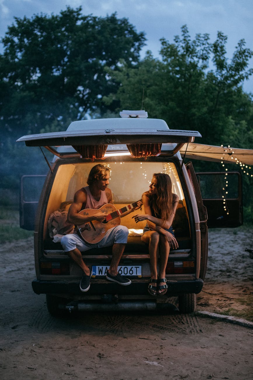 man playing guitar beside a woman in a camper van Romantic Getaway Ideas to Rekindle Your Love