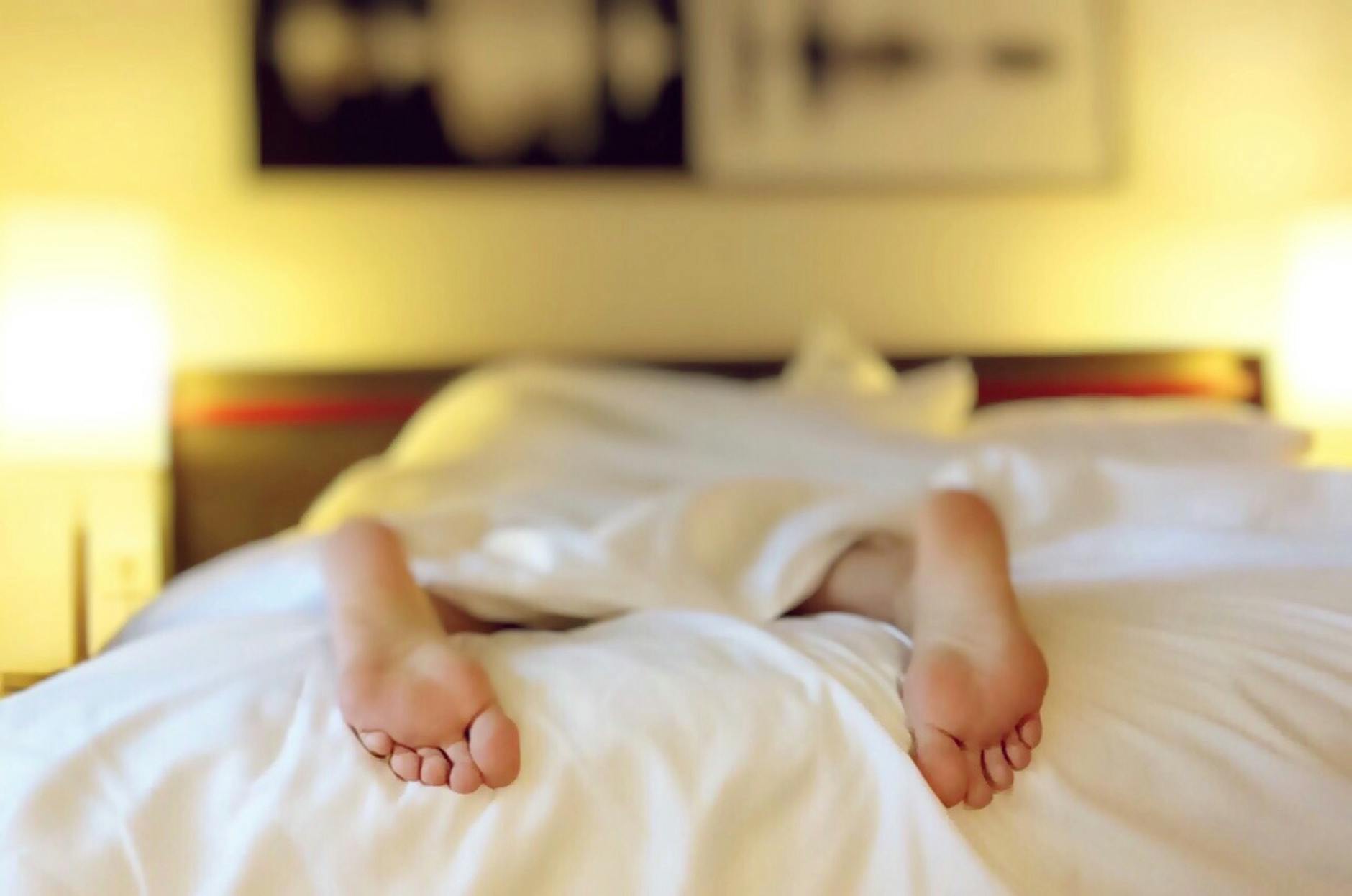 person lying on bed covering white blanket Use Your Phone to Sleep Better: 3 Effective Tips