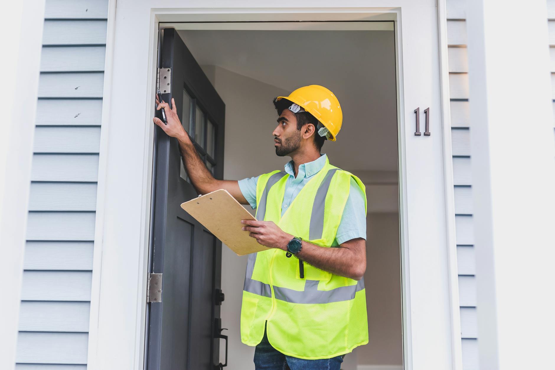 a man in safety vest and hard hat checking the front door New House Problems You Might Not See On Your Home Inspection