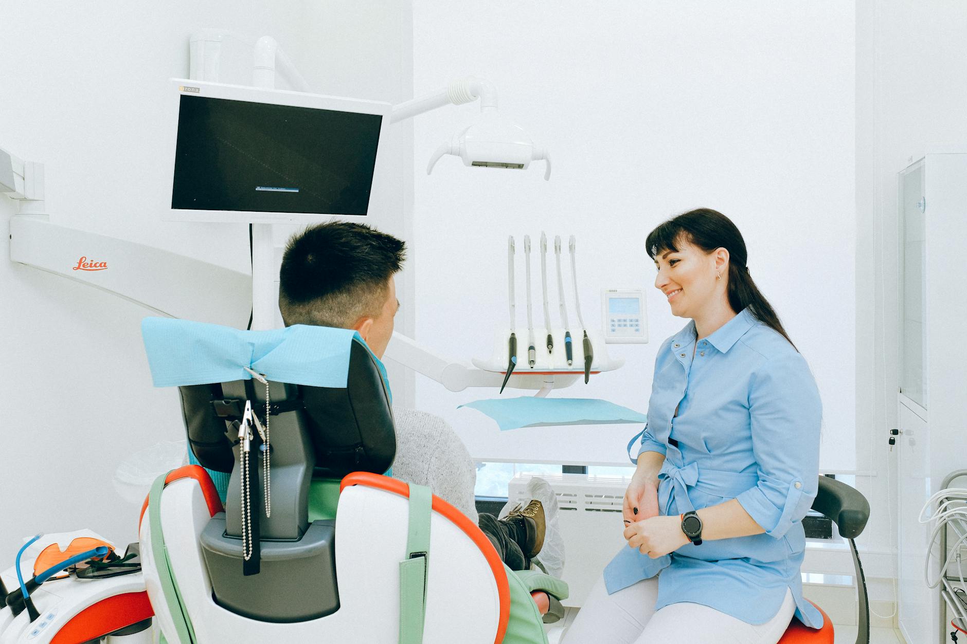 cheerful stomatologist talking with patient sitting in dental chair How to Modernize Your Dental Practice in 2025: Tech, Decor, & Marketing Tips