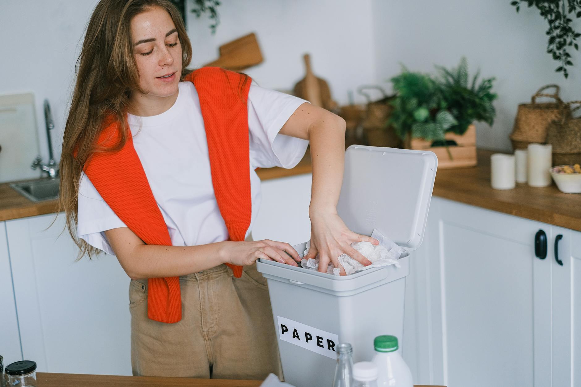 happy woman sorting trash in bin How to Have an Eco-Friendly Home: Ideas to Save Money and Live Sustainably