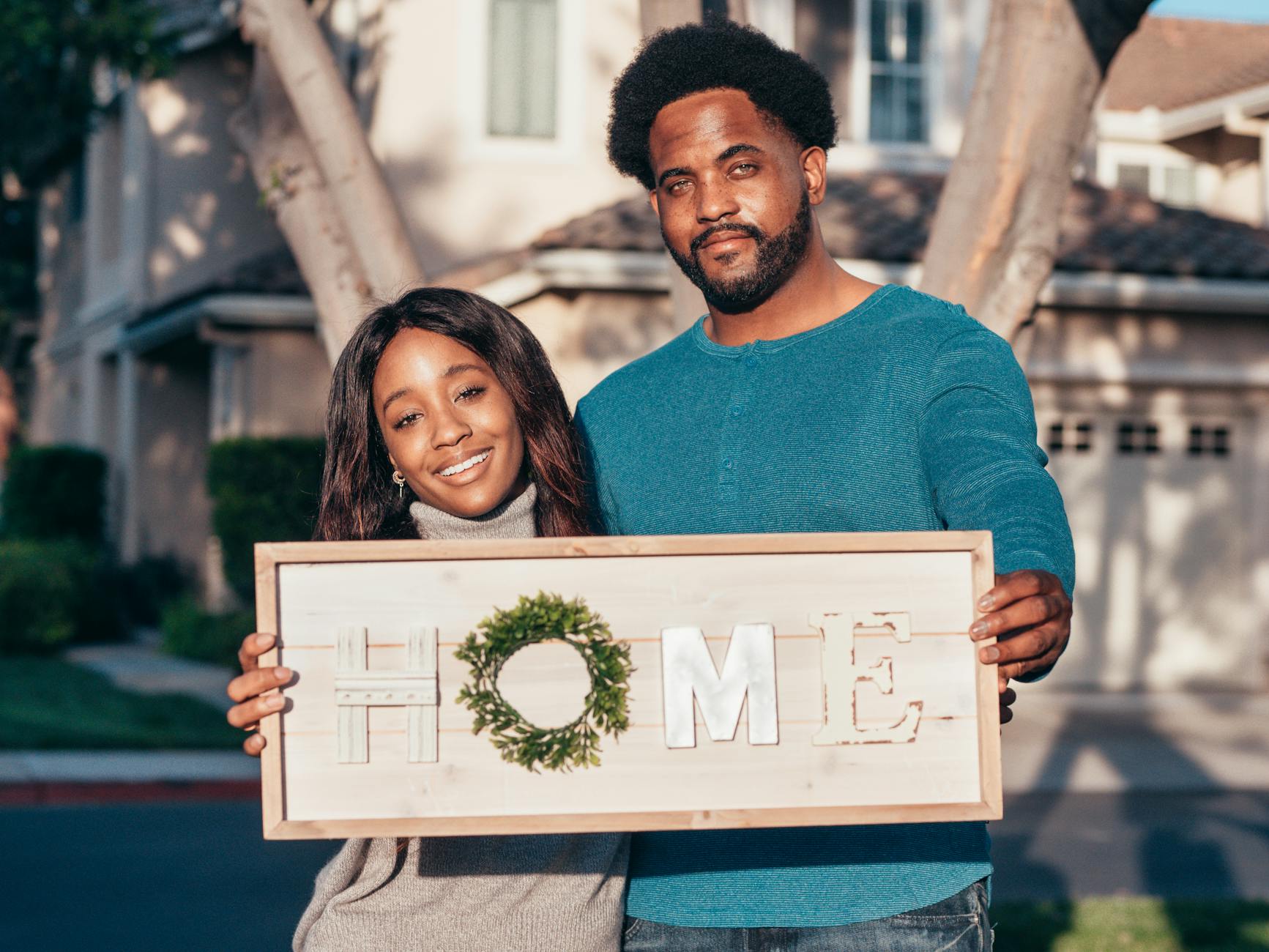 man and woman holding a wooden frame decoration