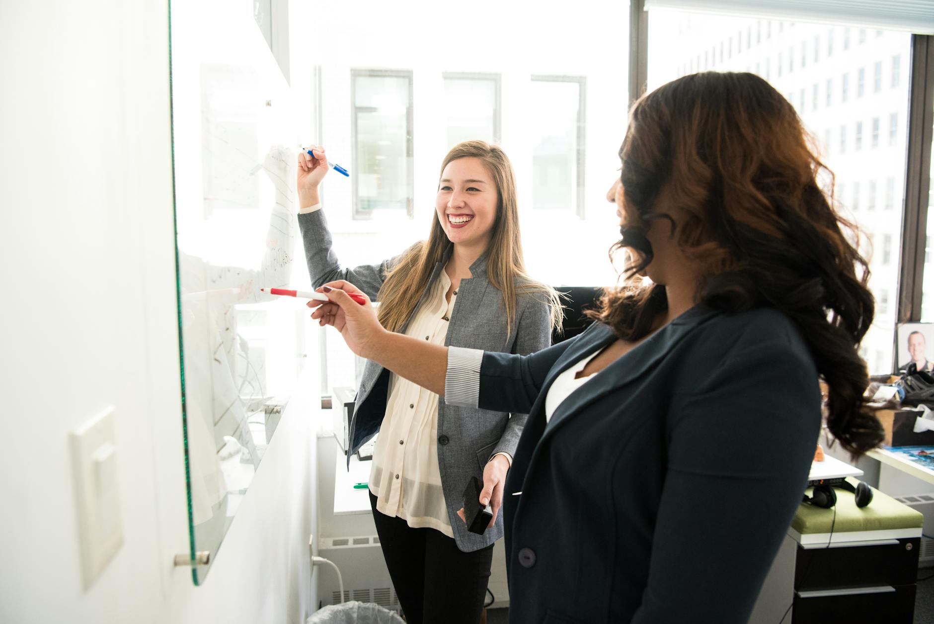 two women in front of dry erase board Small is Big: The Best Small Wins to Boost Your Career Earnings Today
