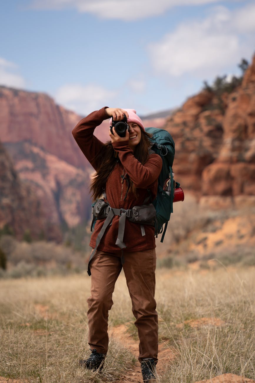 woman hiking and photographing in zion national park in the usa 5 Best Places to Buy Affordable Rural Land in the U.S. Reviewed 2025