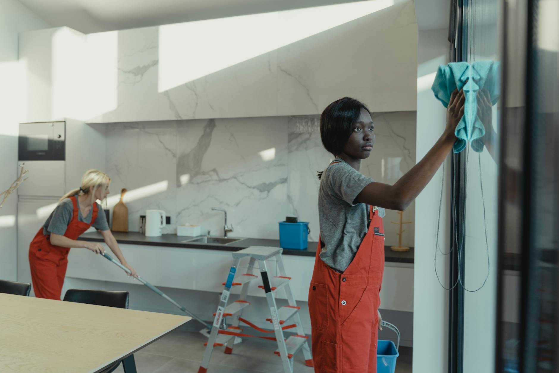 women in gray shirt and orange jumper cleaning the house