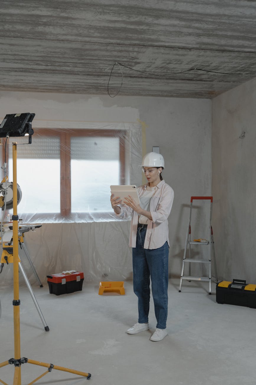 woman wearing white helmet while holding a tablet inside the house 5 Practical Tips to Make Home Renovations Easier (and Less Stressful)
