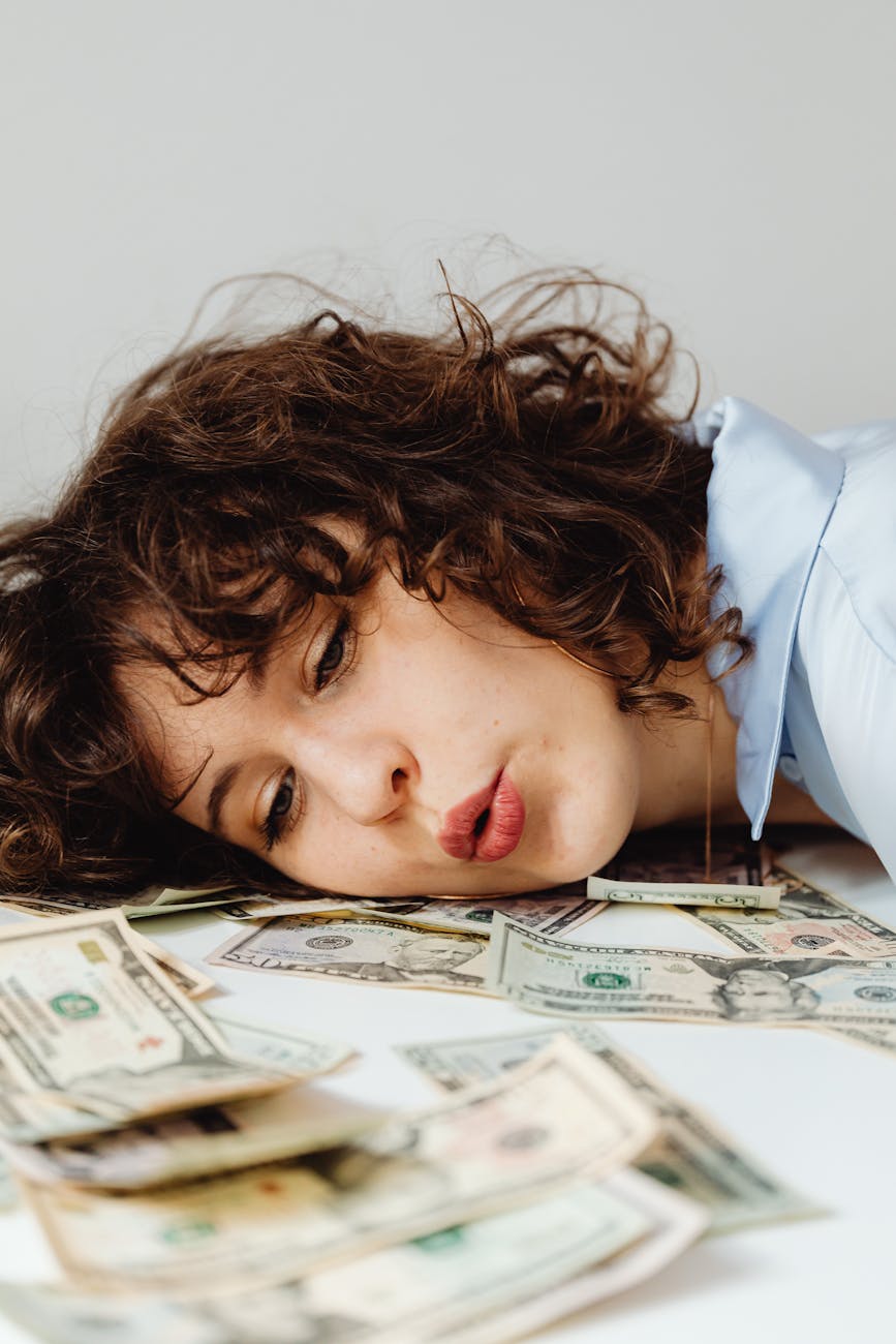 7 Foolproof Strategies to Tackle Your Financial Stress 11 close up shot of a curly haired woman lying her head on paper money 7 Foolproof Strategies to Tackle Your Financial Stress