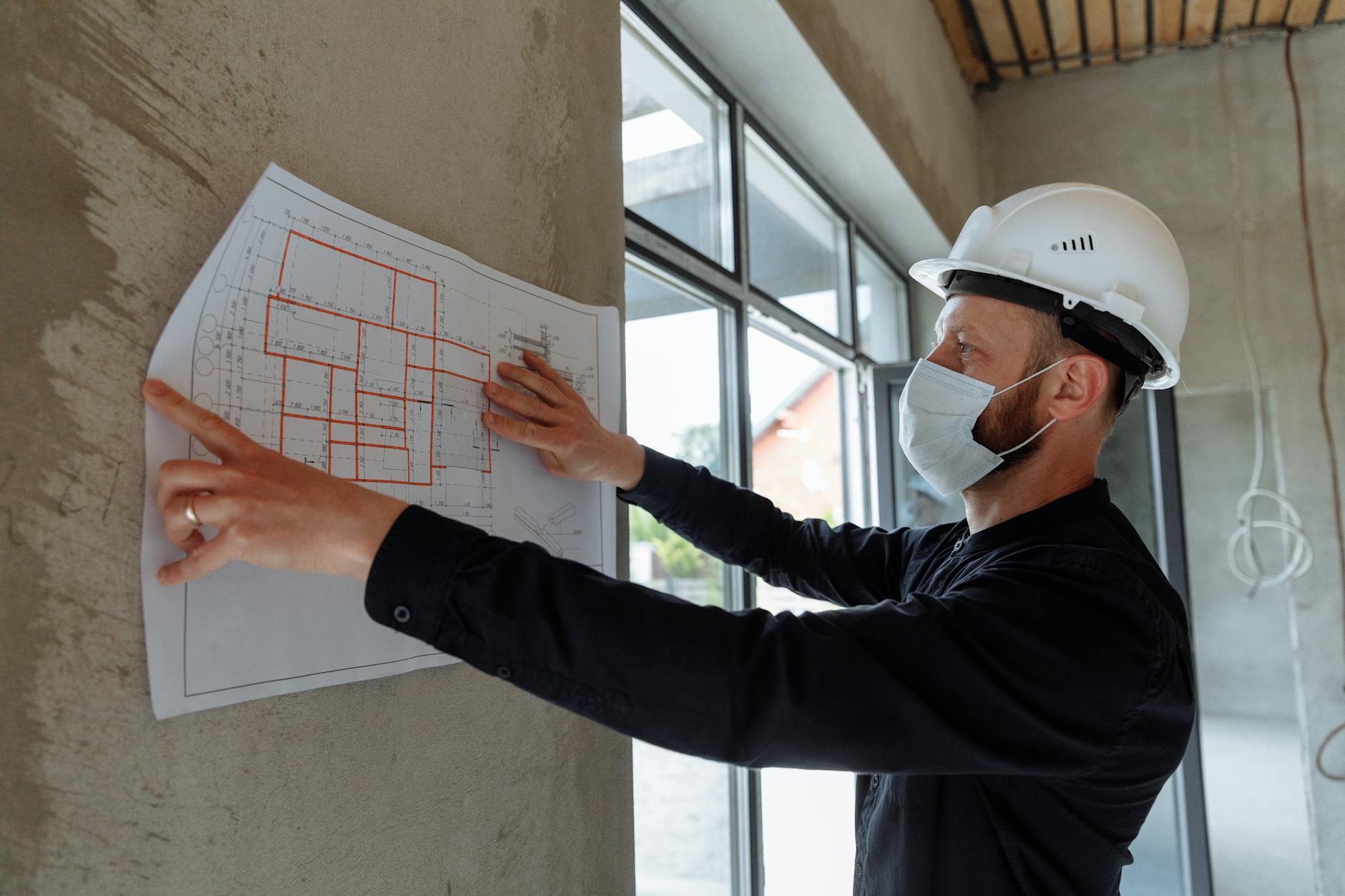 The Biggest Renovation Mistakes People Are Still Making in 2025 11 a man in black long sleeve shirt holding white paper on concrete wall The Biggest Renovation Mistakes People Are Still Making in 2025