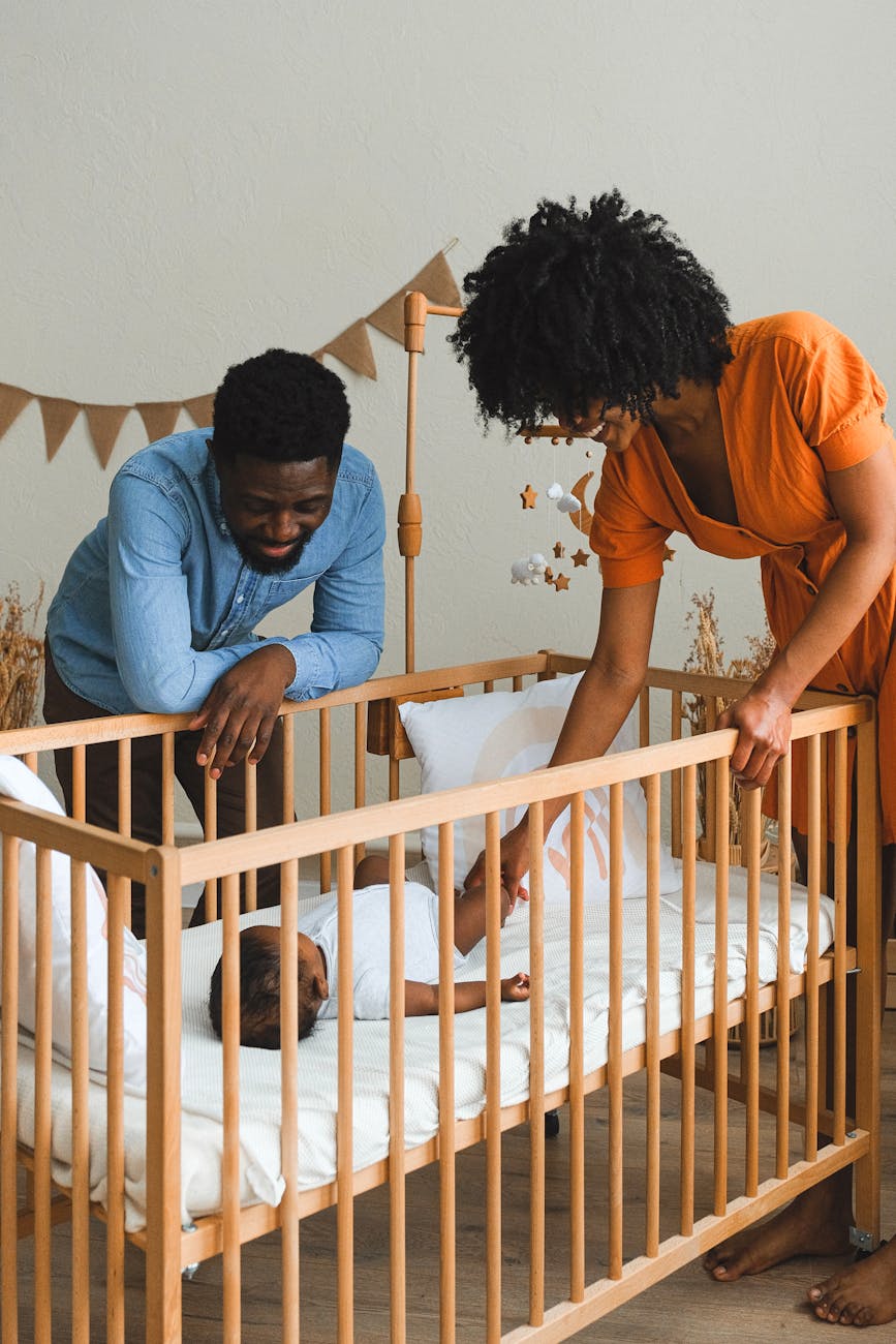 couple watching baby lying in crib How to Create a Kid-Friendly Home Without Sacrificing Style