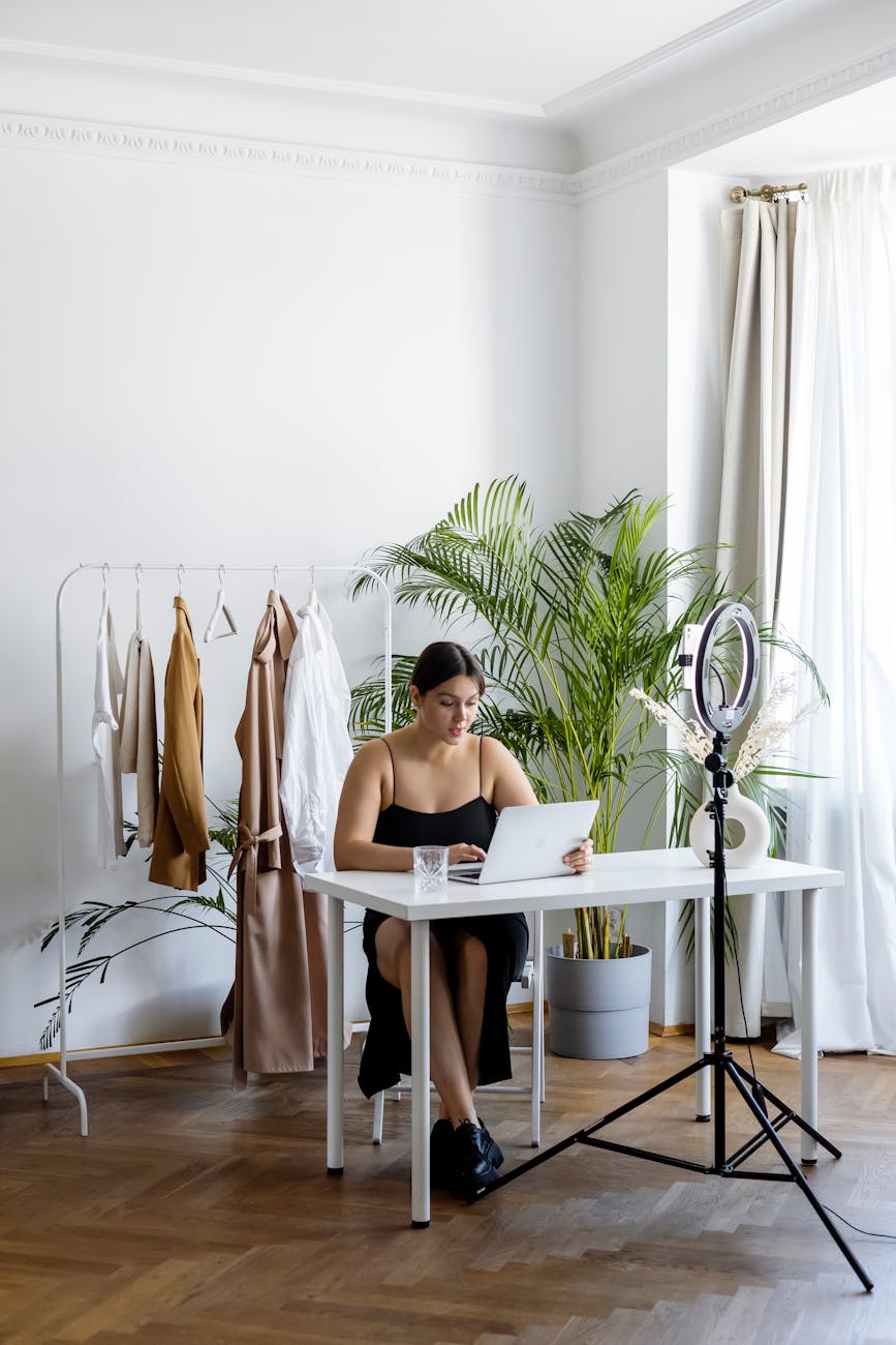 a woman working on her computer while sitting near hanging clothes on a rack Quick Startup Guide to Selling Products Online
