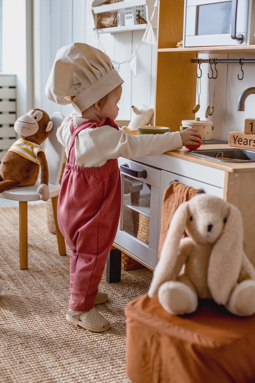 baby in a chef hat playing with a toy kitchen in a chef hat How to Create a Kid-Friendly Home Without Sacrificing Style