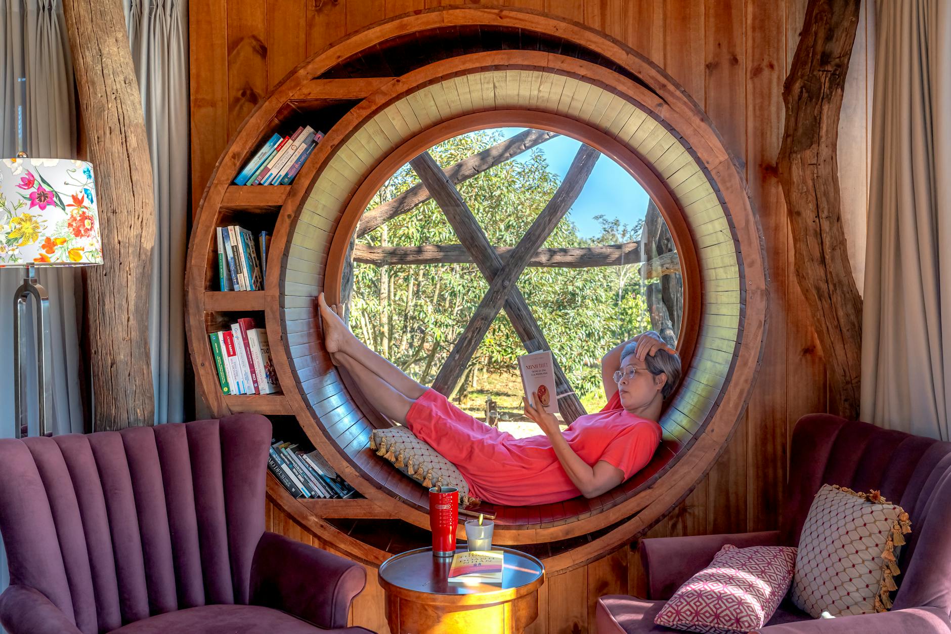 woman lying down on round window in house and reading book