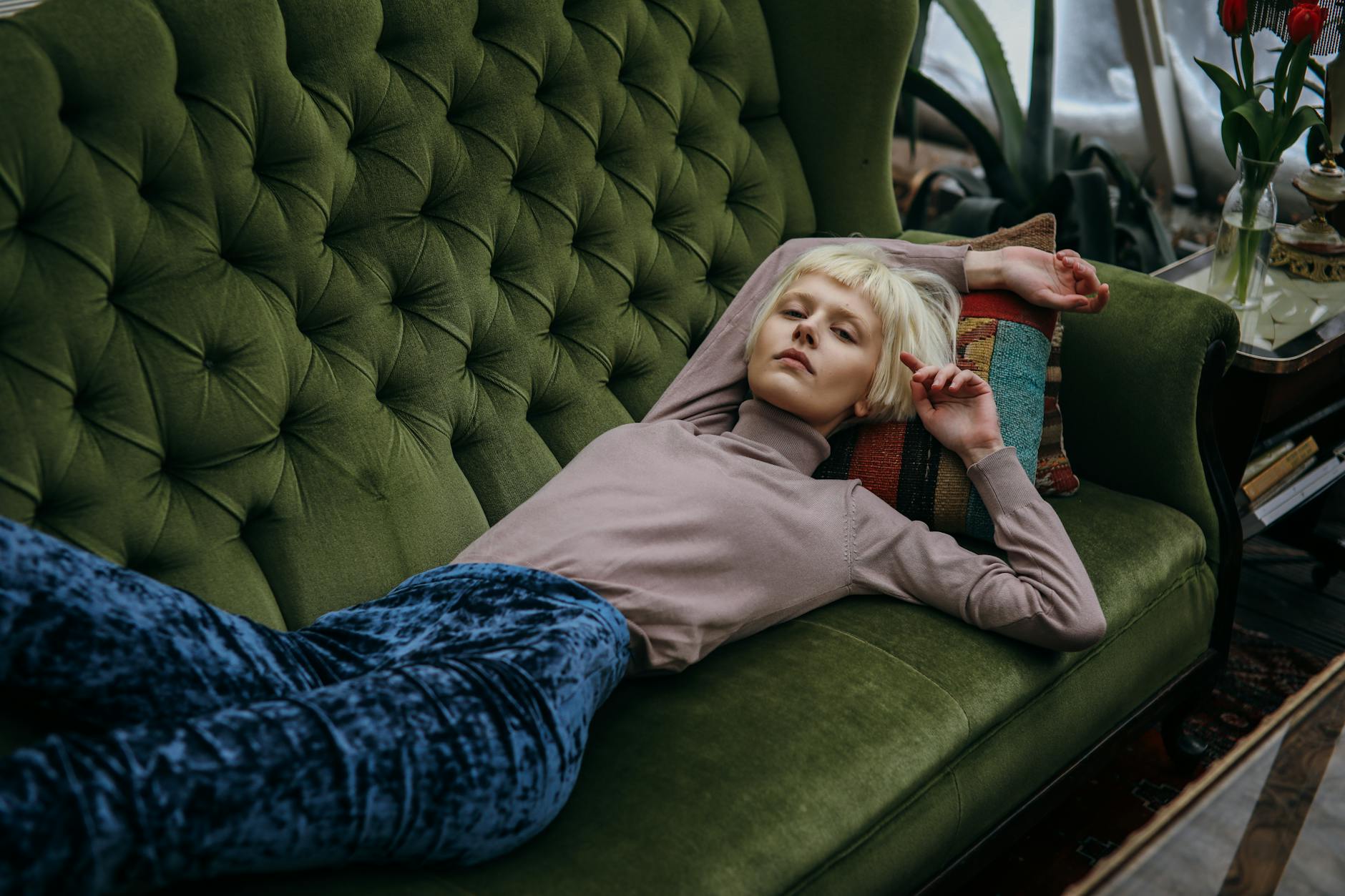 photo of a woman with bleached hair lying on a green sofa Home Sanctuary Design: 8 Ways To Create Your Relaxation Space