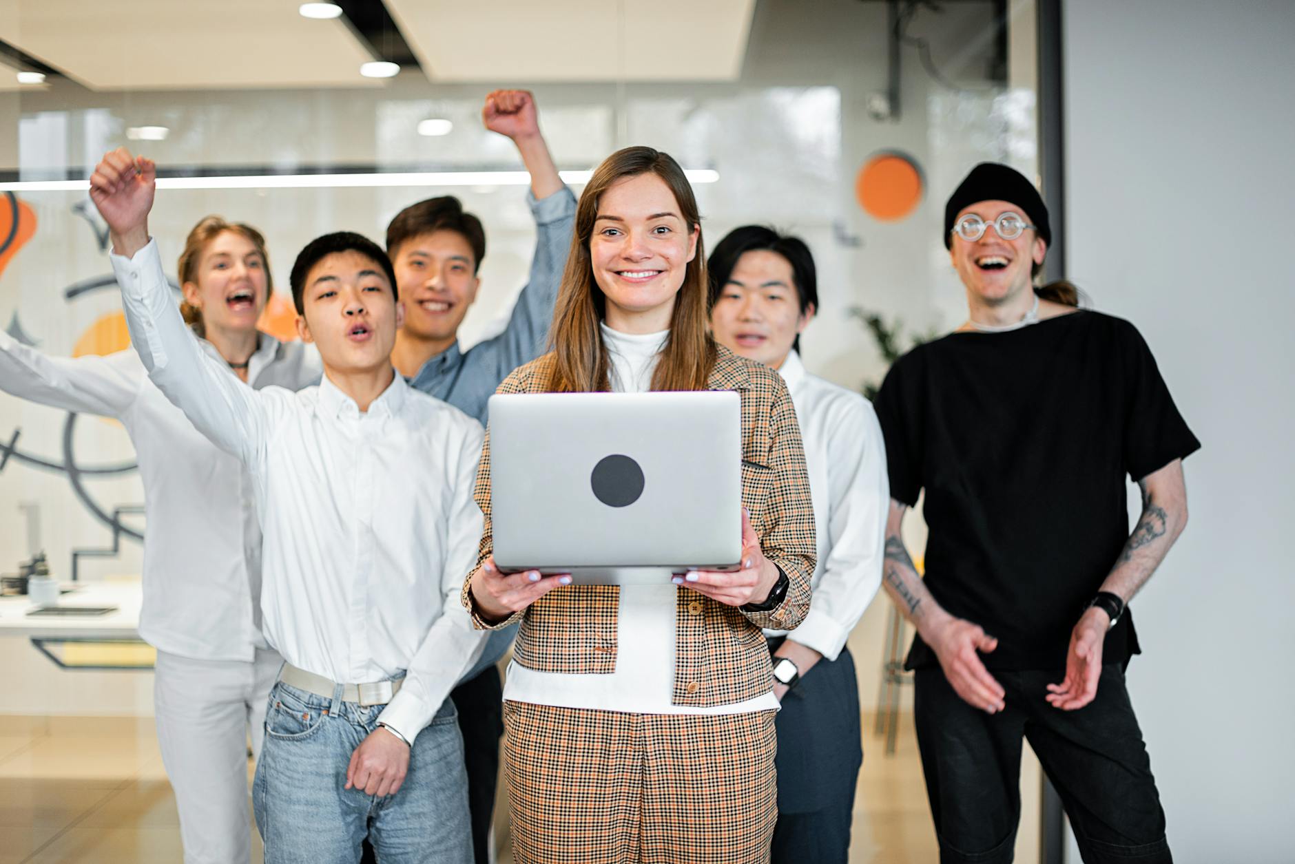 a woman holding laptop in front of her colleagues How To Take Control Of Your Business & Achieve More Success