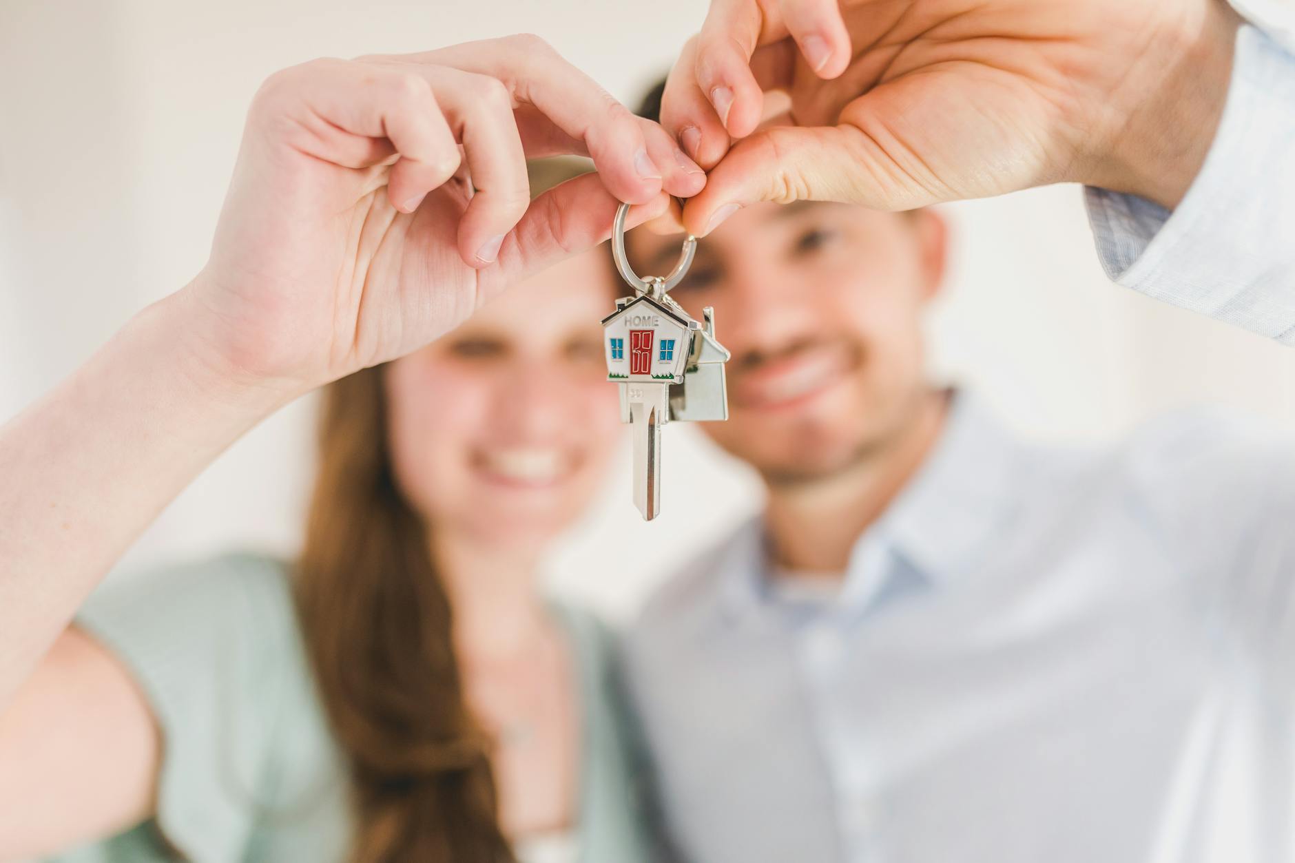 happy couple holding and showing a house key 4 Essential Tips for Buying Your First House