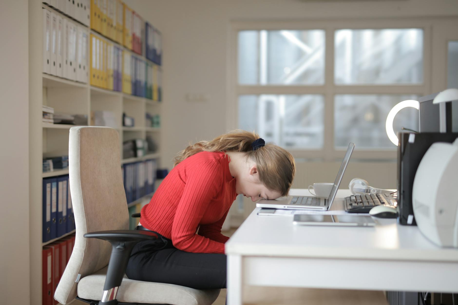 woman in red long sleeve shirt sitting on chair while leaning on laptop Before Offering Mental Health Perks, Fix These Workplace Issues
