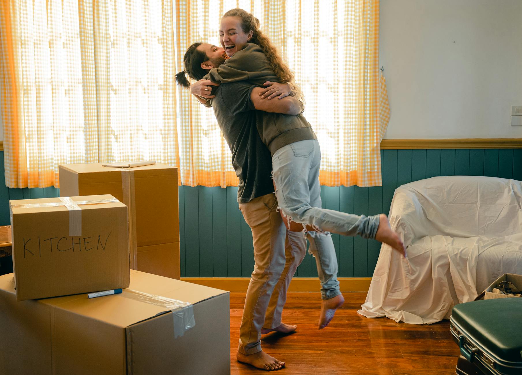 cheerful couple hugging and unpacking carton boxes The Reality of Buying a Home You Should Know