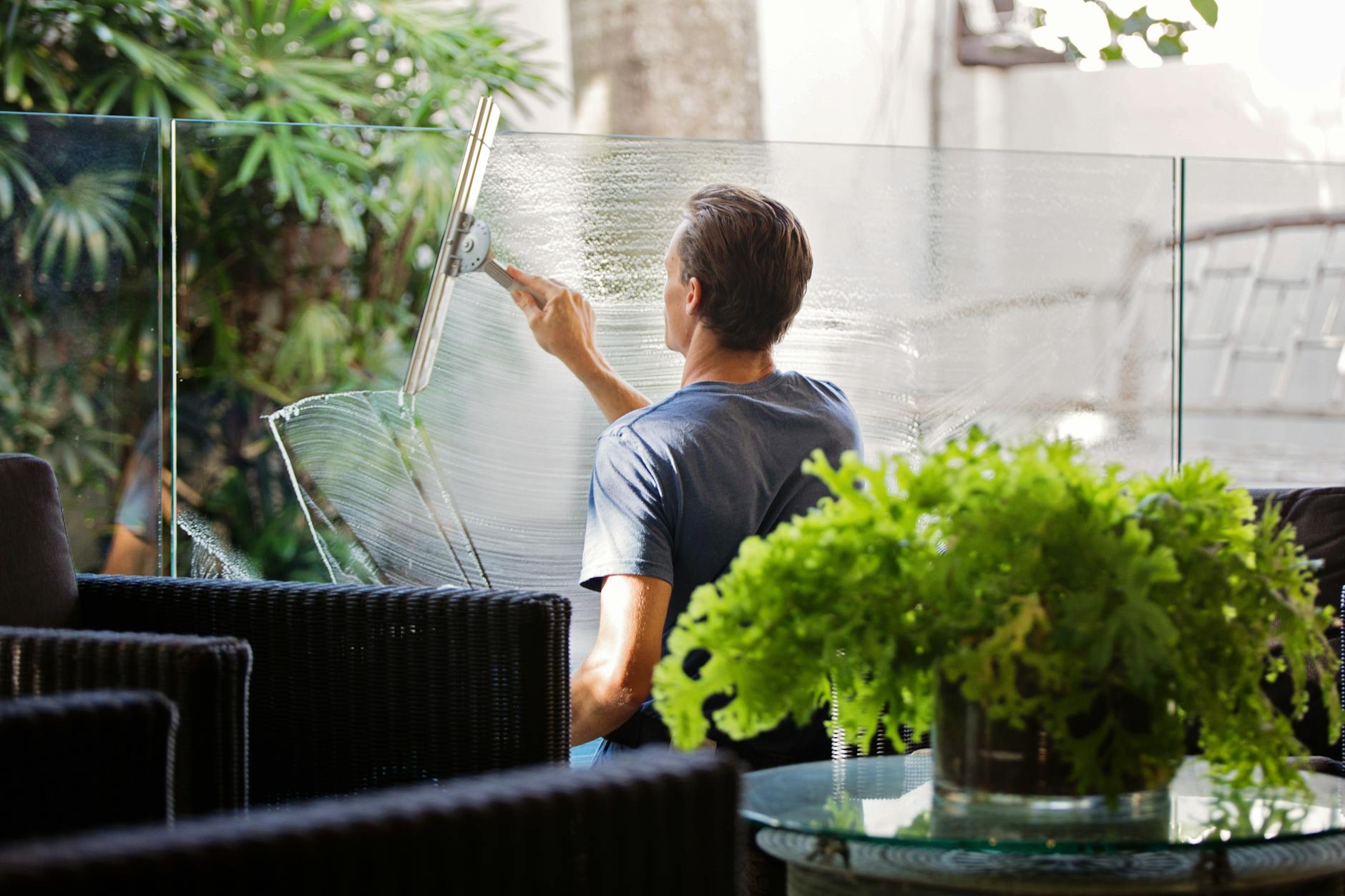 man in gray shirt cleaning clear glass wall near sofa The Family Guide to Moving During Big Life Changes
