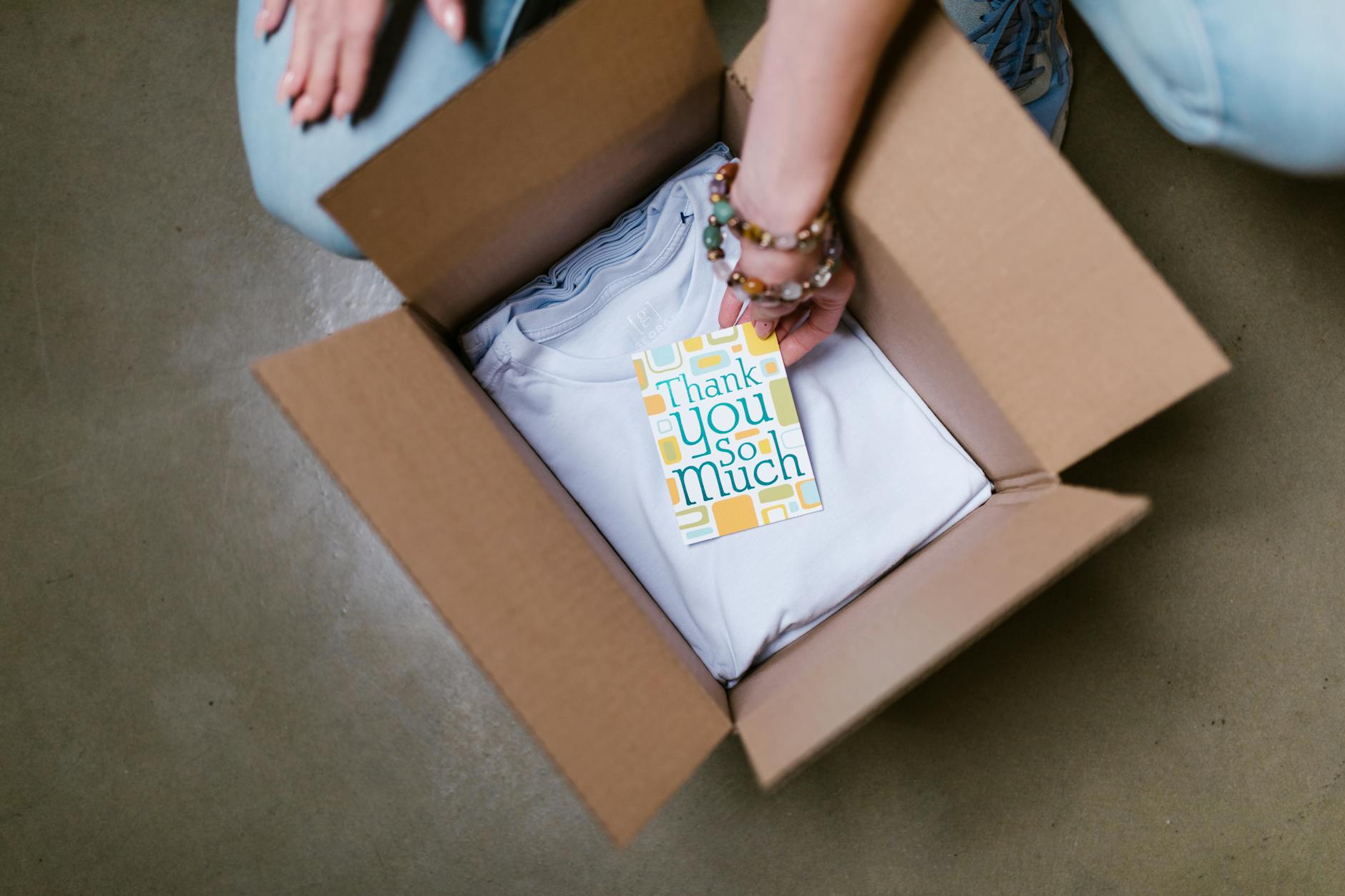 woman putting thank you card into box with t shirts Why Streamlining Sales Orders Improves Customer Trust