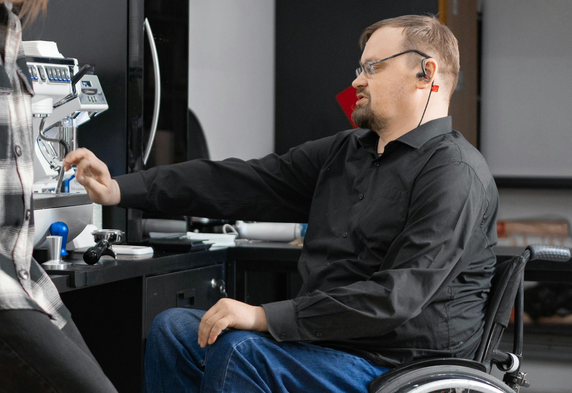 man in black long sleeve shirt sitting on black wheelchair in front of coffee machine Before Offering Mental Health Perks, Fix These Workplace Issues