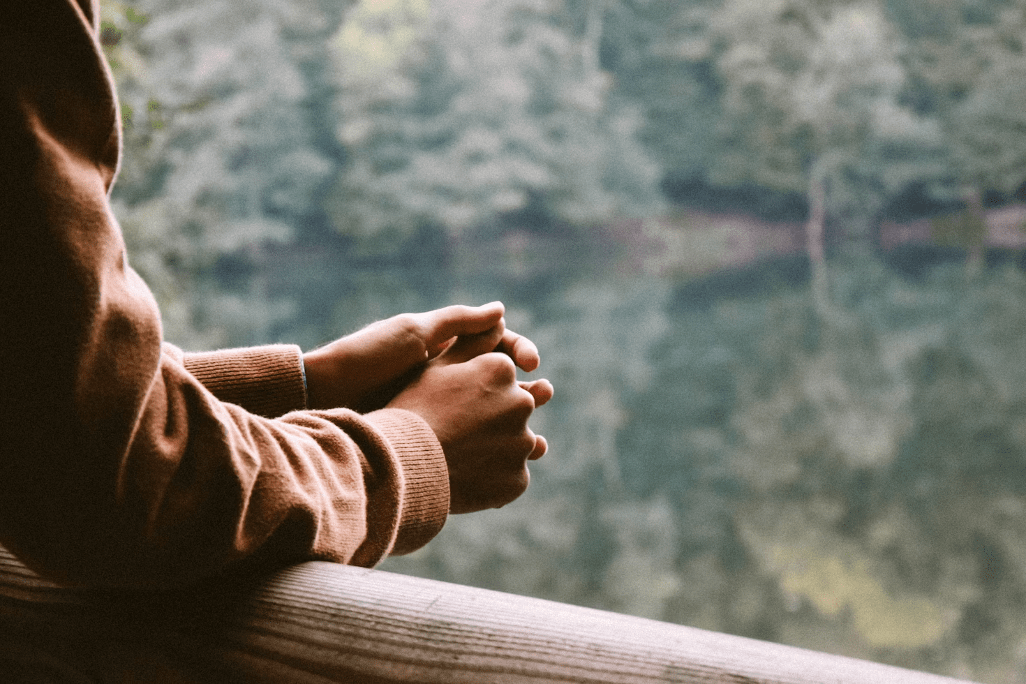 7 Proven Calming Techniques for Your Racing Mind 7 Close-up of a person with crossed arms resting on a wooden railing, looking out over a tranquil water surface surrounded by trees. Calming Techniques for When Your Thoughts Feel Out of Control