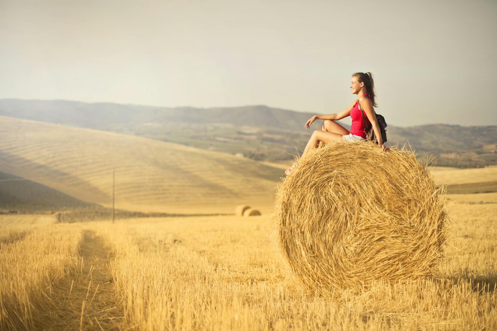 woman in red tank top sitting hay roll 9 Tips to Plan Ahead for the Next Farming Season