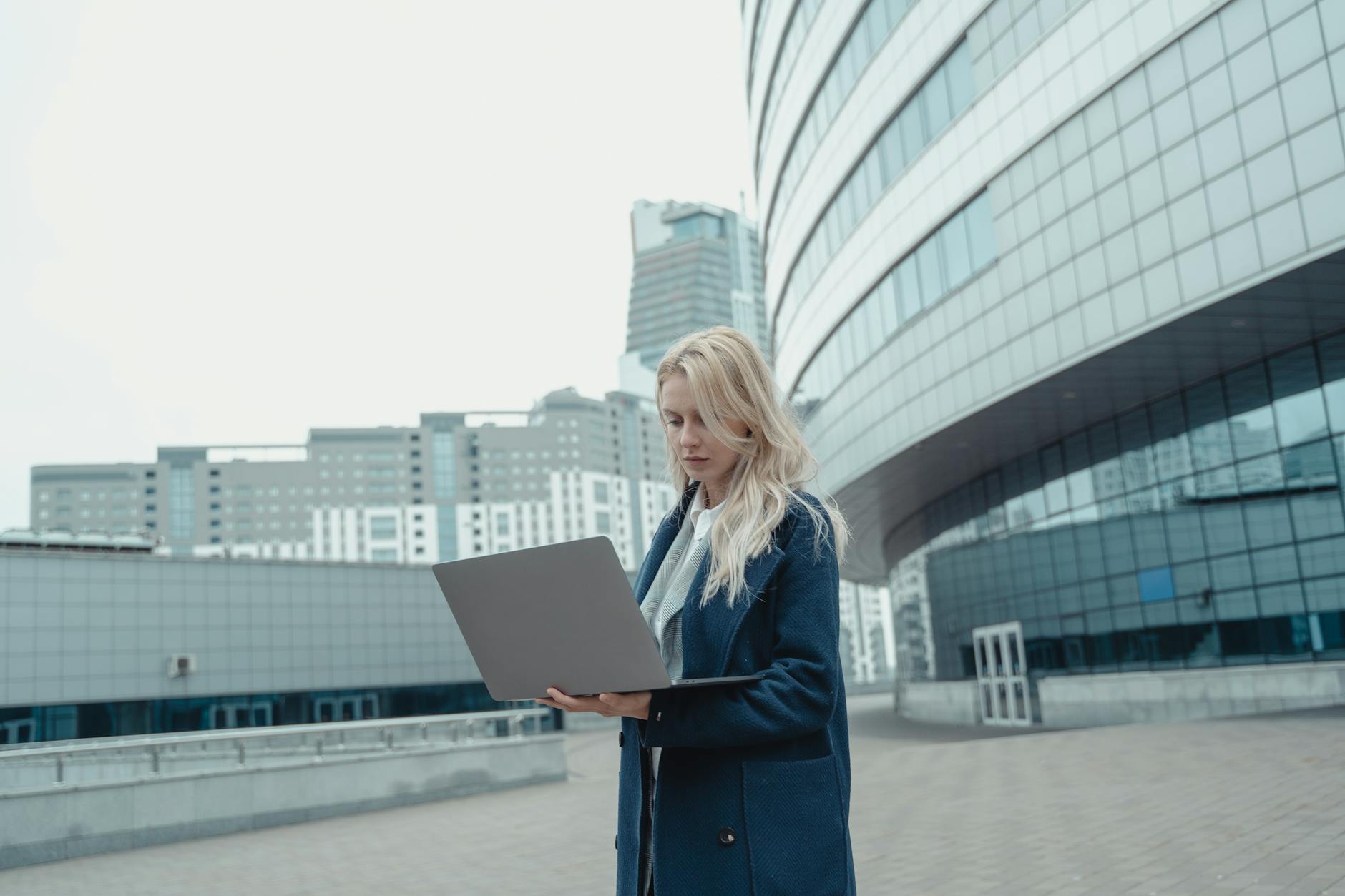 woman in blue coat standing near the high rise building Tech Troubles Slowing Your Business Down? Here’s 8 Ways to Fix Them