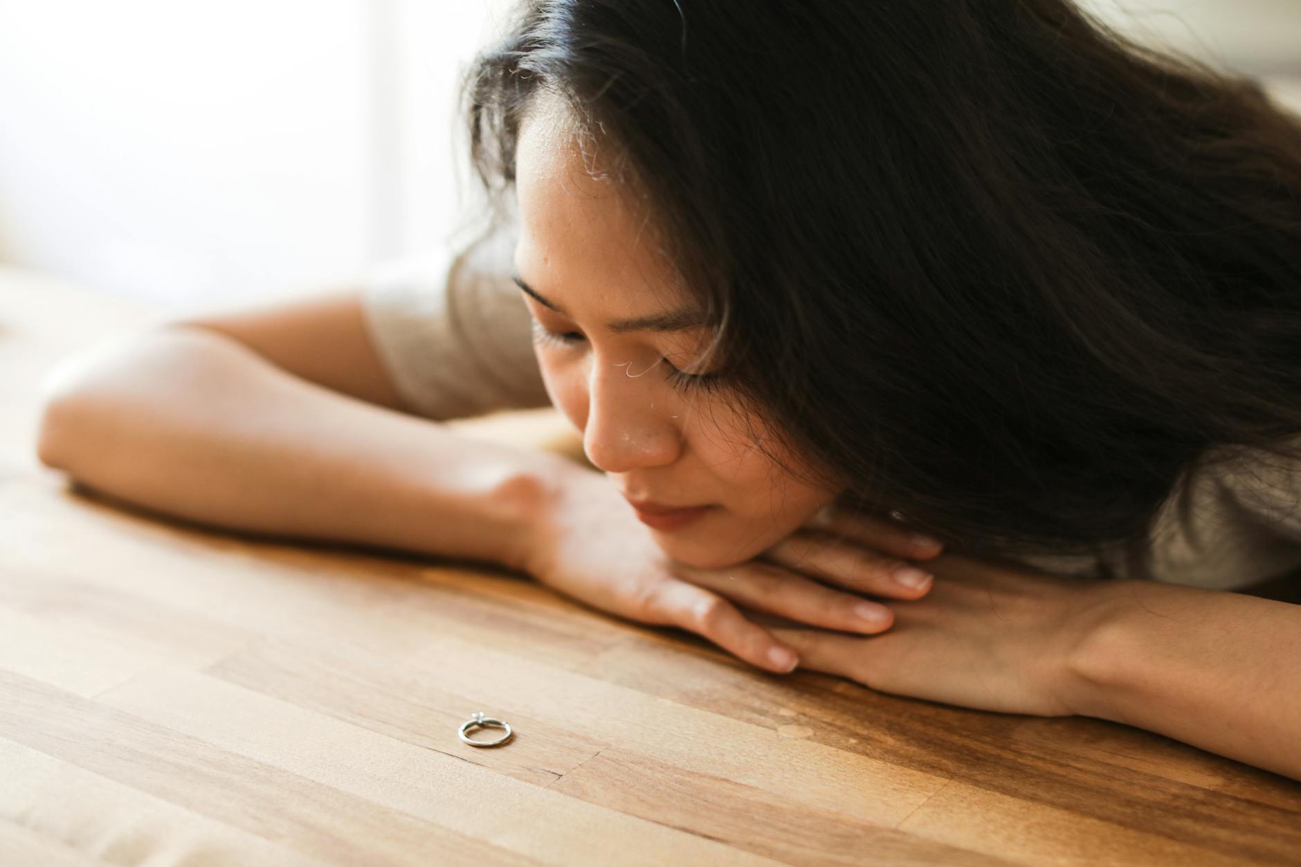 a woman crying near the wooden table while looking at the ring How to Navigate Divorce: Emotional, Legal, and Financial Realities