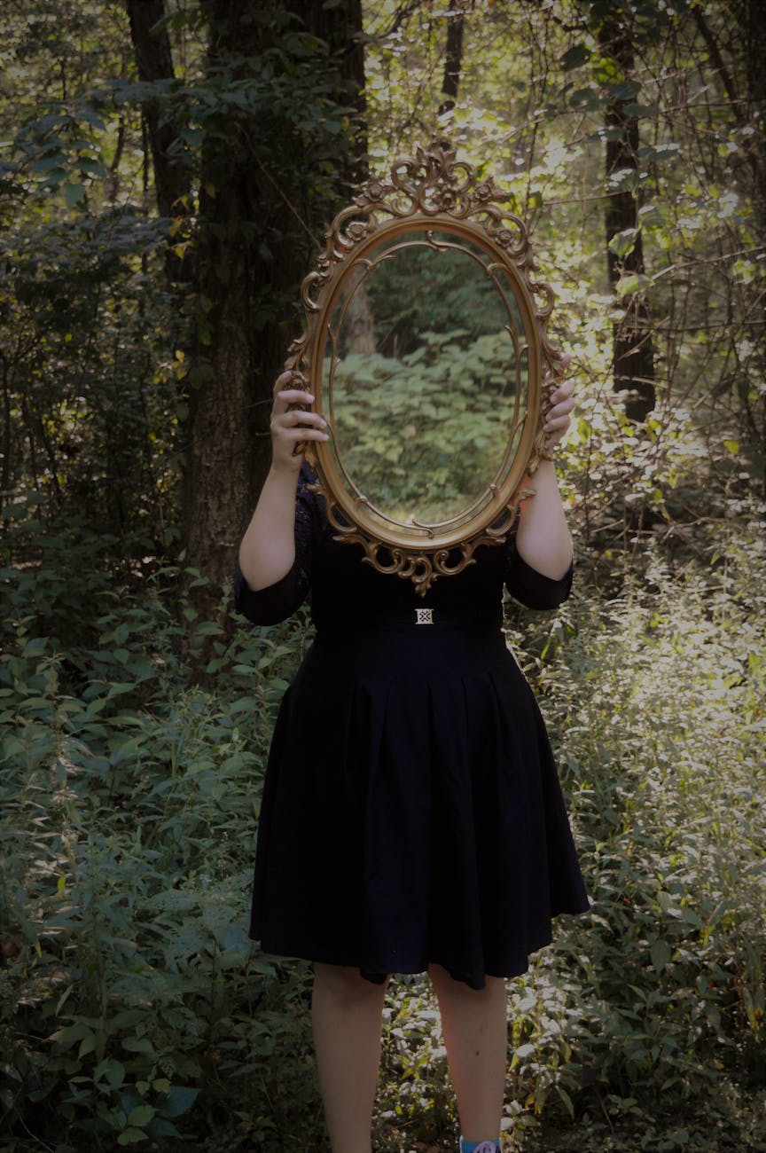 6 Empowering Ways to Reclaim How You Feel About Yourself 10 woman holding mirror against her head in the middle of forest 6 Empowering Ways to Reclaim How You Feel About Yourself