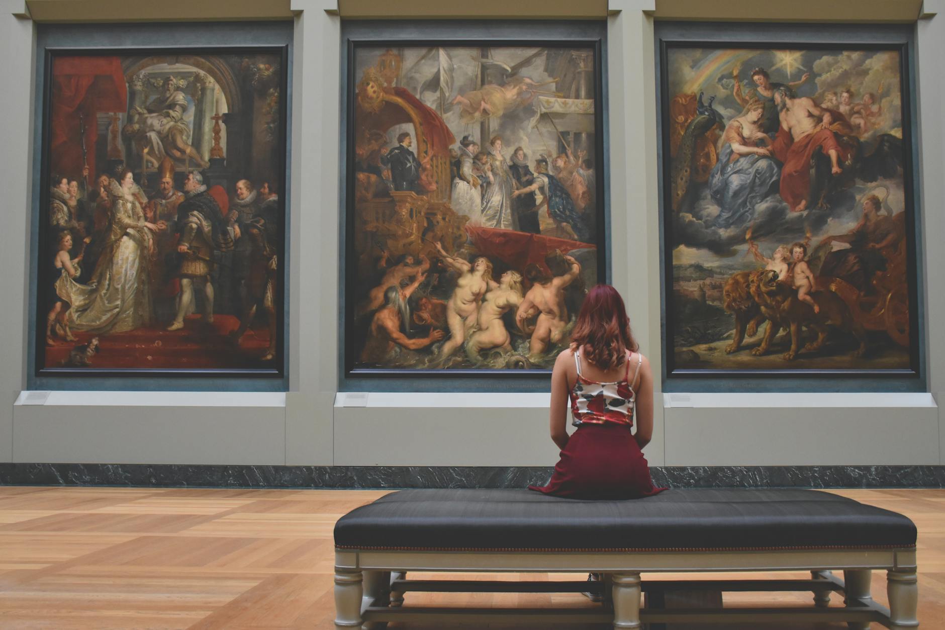 woman sitting on ottoman in front of three paintings Rediscover Yourself: 10 Gentle Ways to Reconnect with Who You Are