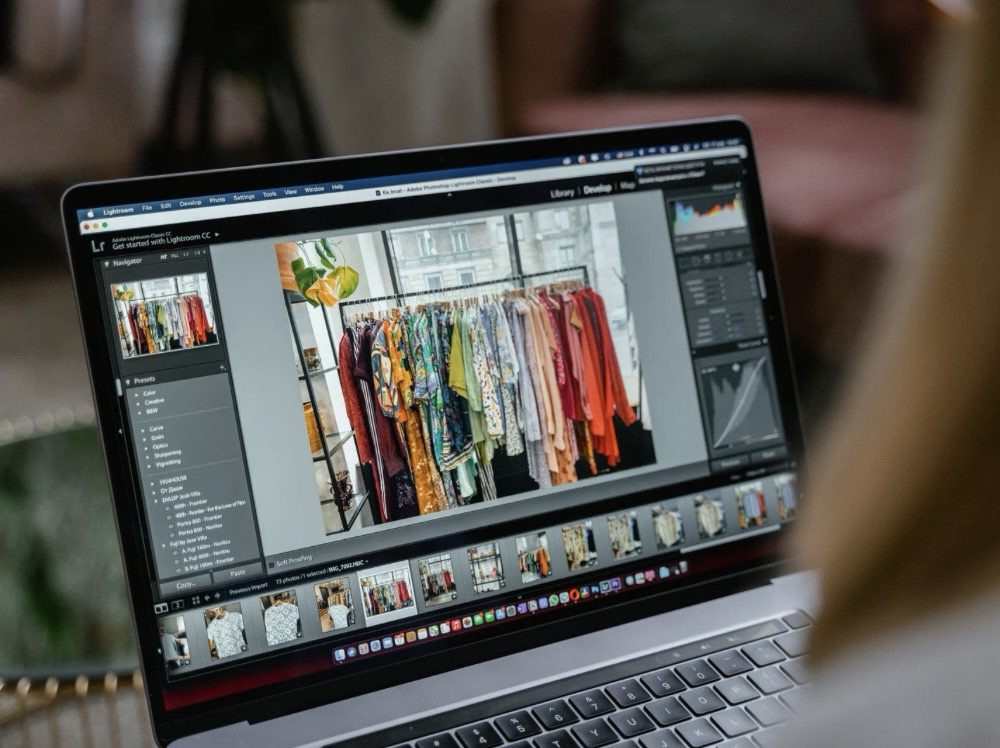 A close-up of a laptop screen displaying Adobe Lightroom with a vibrant clothing rack in the background, featuring colorful garments. 10 Proven Tips for Finding Help with Your Marketing Strategy