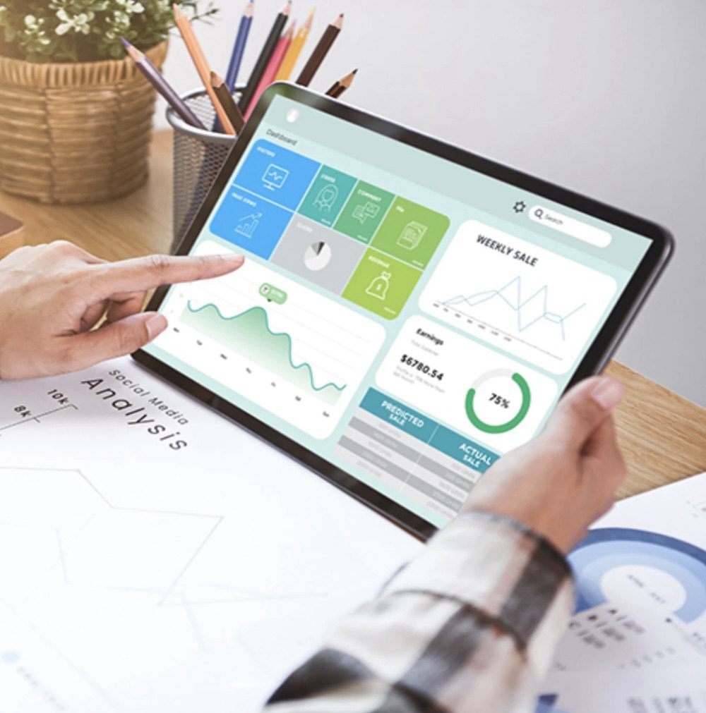 A person analyzing marketing data on a tablet, displaying various charts and performance metrics, with a notebook and colored pencils in the background. 10 Proven Tips for Finding Help with Your Marketing Strategy