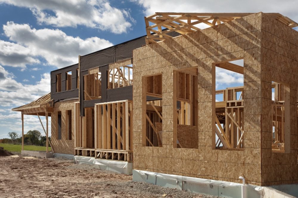 Is Building Your Own Home the Ultimate Dream or a Costly Mistake? 11 Construction site of a house showing wooden framing and walls in progress, with a clear blue sky and scattered clouds. Is Building Your Own Home the Ultimate Dream or a Costly Mistake?