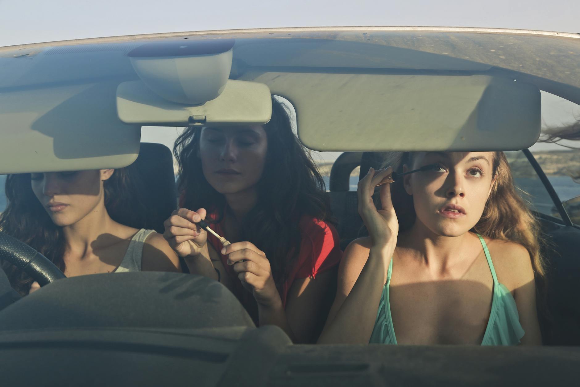 three friends in car applying makeup Sustainability Mindset: 7 Ethical Ways to Cut Carbon on Your Commute