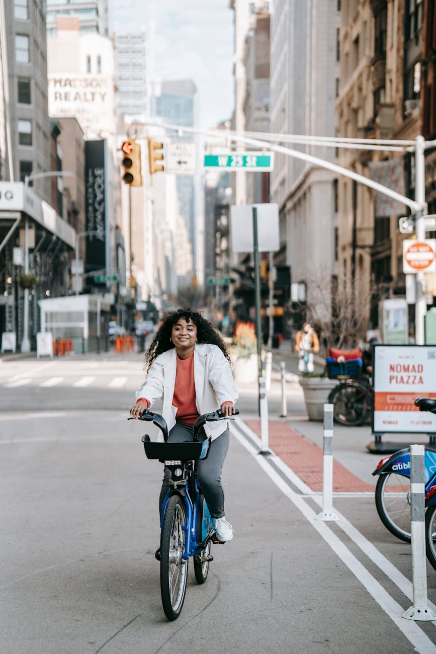 smiling black woman riding bicycle on city street Sustainability Mindset: 7 Ethical Ways to Cut Carbon on Your Commute