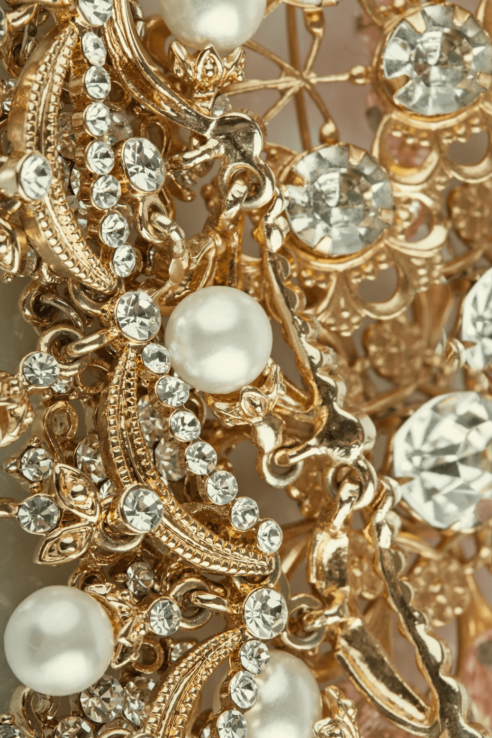 Close-up view of ornate gold jewelry featuring intertwined designs, sparkling rhinestones, and a single pearl, showcasing intricate craftsmanship. Best Diamond Gold Stud Earrings for Women