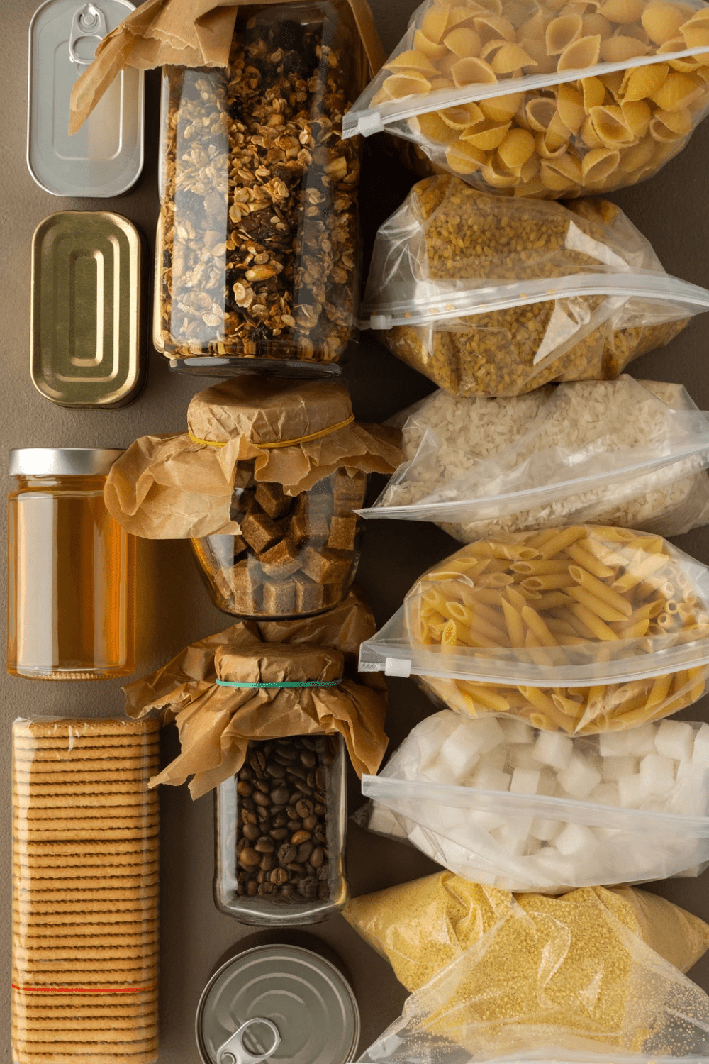 An organized collection of pantry staples, including jars and bags filled with grains, pasta, sugars, and snacks, arranged neatly on a shelf. 30 Essential Winter Pantry Staples for a Self-Sufficient Kitchen